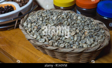 Grüne Kaffeebohnen enthalten die meisten Koffein - in einem hölzernen Warenkorb Stockfoto