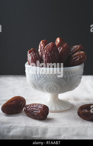 Schüssel medjool Datteln in einer weißen Schüssel mit seitlicher Beleuchtung. Stockfoto