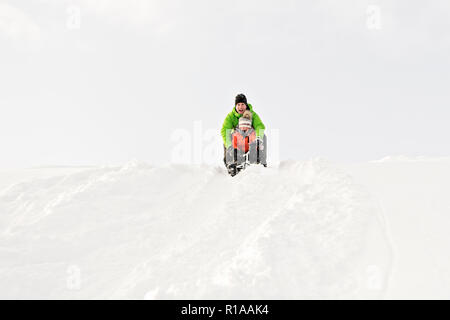 Ein netter Vater und Sohn auf dem Schlitten sitzen Stockfoto