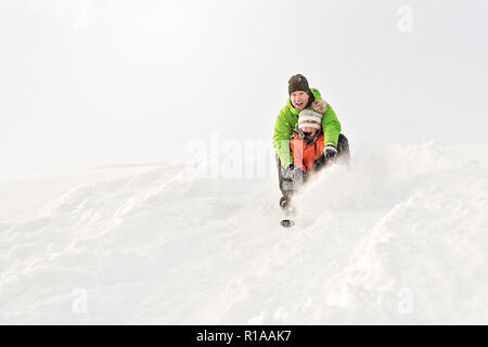 Ein netter Vater und Sohn auf dem Schlitten sitzen Stockfoto