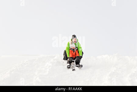 Ein netter Vater und Sohn auf dem Schlitten sitzen Stockfoto