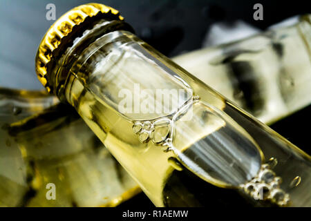 Bier in Flaschen mit Blasen in Eiswürfel closeup auf einem dunklen Hintergrund Stockfoto