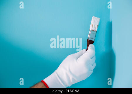 Bild der Mann hält Pinsel vor der blauen Wand. Stockfoto