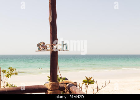 Holz- Strand anmelden Sommer Strand Inschrift, Rest, Sand, Meer. Holz- Plakette mit der Aufschrift Strand auf einer Platte, Meer Hintergrund. Berufung Dekorationen. Stockfoto