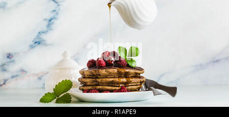 Banner von Gießen Ahorn Sirup über Glutenfreie grün Buchweizen Pfannkuchen mit frischen Beeren. Lecker Veganes Frühstück ohne Eier, Mehl und raffiniert Stockfoto