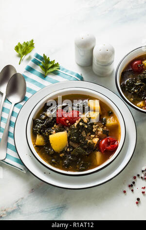 Veganer winter Grünkohl Kartoffelsuppe mit Buchweizen, Cherry Tomaten und Kartoffeln. Lecker voll Gemüse Lebensmittel für die ganze Familie. Stockfoto