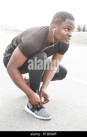 Junge Sportler auf Sport Schuhe Schnürsenkel binden. Fit, Fitness, Bewegung, Training und gesunde Lebensweise. Stockfoto