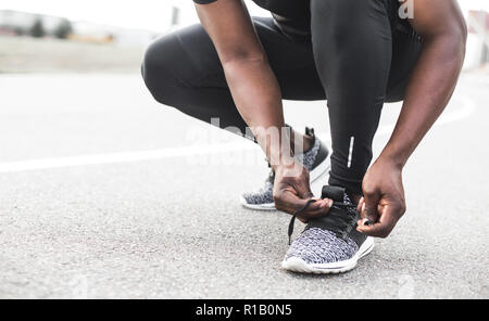 Junge Sportler auf Sport Schuhe Schnürsenkel binden. Fit, Fitness, Bewegung, Training und gesunde Lebensweise Konzept. freier Platz für Text Stockfoto