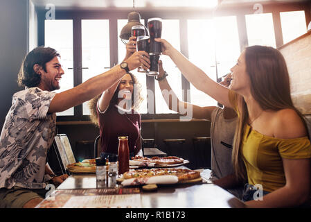Eine Gruppe von Freunden einen Toast mit Soft drink Gläser im Restaurant. Junge Menschen an einem Tisch mit dem Essen sitzen, toasten Getränke und Speisen Stockfoto