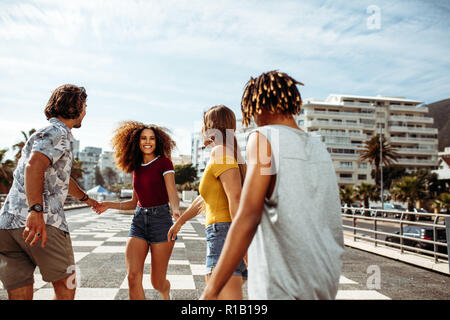 Schöne Frau Wandern mit Freunden im Freien halten sich an den Händen. Gruppe von multi-ethnischen Männer und Frauen, die gemeinsam Spaß im Freien. Stockfoto