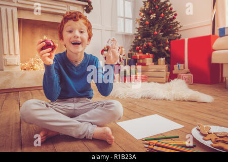 Freudige Junge über Zeichnung Weihnachtsschmuck aufgeregt Stockfoto