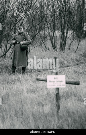 Gomel, Belarus - November 26, 2017: Soldat der Wehrmacht steht auf der Straße, im Vordergrund ein Kreuz der Grab-Rekonstruktion der Schlachten für Th Stockfoto