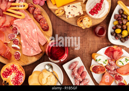 Charcuterie Verkostung. Ein Foto von vielen verschiedenen Wurst und Schinken, Aufschnitt und einer Käseplatte, geschossen von oben auf eine rustikale Hintergrund mit einem gla Stockfoto