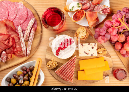 Charcuterie Verkostung. Ein Foto von vielen verschiedenen Wurst und Schinken, Aufschnitt, und eine Käseplatte, geschossen von oben auf eine rustikale Hintergrund mit einem gl Stockfoto