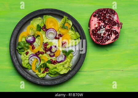 Gesunde Ernährung, frischer Salat mit lila Zwiebel und Granatapfel Samen auf grünem Hintergrund Stockfoto