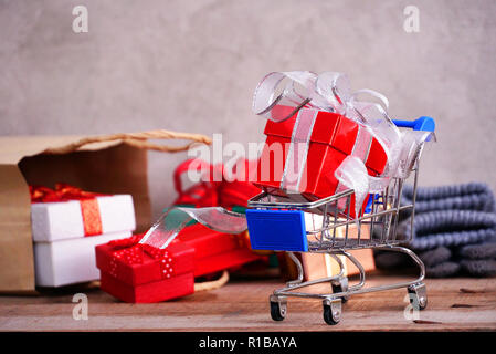 Roter Geschenkbox auf kleinen Wagen mit Hintergrund Geschenkboxen Herausspritzen von Papiertüte, Shopping Konzept. Stockfoto
