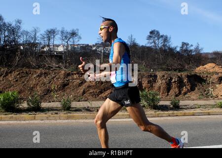 Athen, Griechenland. 11 Nov, 2018. Die Teilnehmer laufen hinter einem verbrannten Fläche von Mati Dorf, wo 99 Menschen bei einem Waldbrand im letzten Sommer gestorben, während der Athen Marathon 2018. (Bild: © aristidis VafeiadakisZUMA Draht) Stockfoto