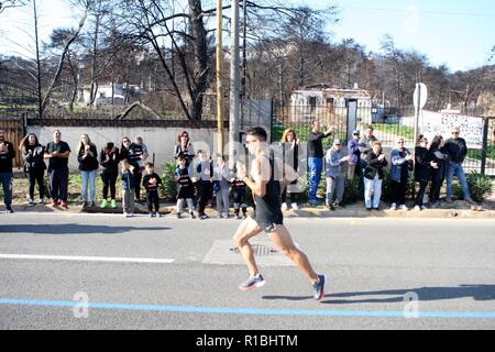 Athen, Griechenland. 11 Nov, 2018. Die Teilnehmer laufen hinter einem verbrannten Fläche von Mati Dorf, wo 99 Menschen bei einem Waldbrand im letzten Sommer gestorben, während der Athen Marathon 2018. (Bild: © aristidis VafeiadakisZUMA Draht) Stockfoto