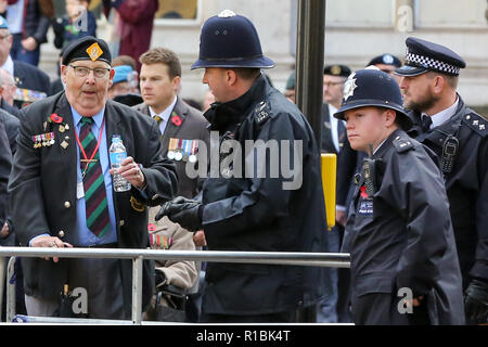 Westminster, London, Großbritannien, 11. Nov. 2018 - Polizisten hilft einem Veteranen nach der Einnahme während der Prozession krank. Kriegsveteranen, nehmen an der jährlichen Erinnerung Sonntag auf das 100-jährige Jubiläum des Waffenstillstandes Prozession Tribut zu denen, die gelitten haben oder während des Krieges starb zu bezahlen. Credit: Dinendra Haria/Alamy leben Nachrichten Stockfoto