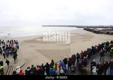 Folkestone, Kent, Großbritannien. 11 Nov, 2018. Krieg dichter Wilfred eigenen Gesicht schließlich entstand aus dem Strand an der sonnigen Sand, die Sonne kam raus. Danny Boyle kamen an die 100 Menschen versammelt, um den Waffenstillstand Jahrestages zu gedenken. Credit: Monica Wells/Alamy leben Nachrichten Stockfoto