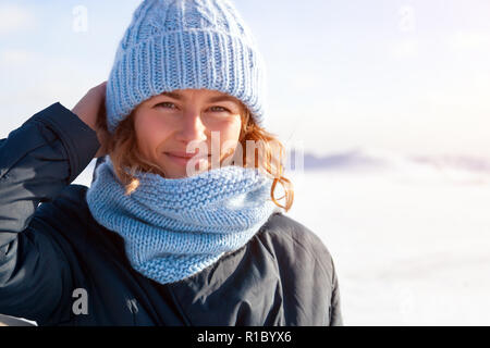 Close up Portrait von Schönheit Frau im frostigen stilvolle Mantel um gefrorene Meer und Stein. Schöne junge Frau in Blau Schal, gewellt Tolle Frisur, Stockfoto