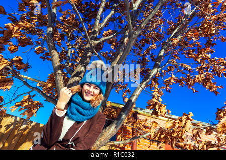 Close up Portrait von Schönheit Frau im frostigen stilvolle Mantel um einen Baum mit vergilbten Blätter. Schöne junge Frau in Blau Schal, gewellt erstaunliche Haar Stockfoto