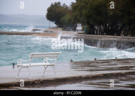 Leeren Bank durch die stürmische See von der Welle in Dalmatien Stadt am Meer in der Nebensaison bei starkem Südwind spritzte Stockfoto