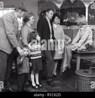 1967, Grundschule, Eltern und Großeltern eines Kindes im Gespräch mit einer Lehrerin in einem Klassenzimmer, der trägt eine Blume gemusterten mini-kleid, England UK. Stockfoto