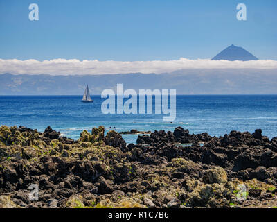 Bild von einer Klippe mit einem Segelboot in den Atlantik und die Insel Pico mit Berg Pico im Hintergrund Azoren Portugal Europa Stockfoto