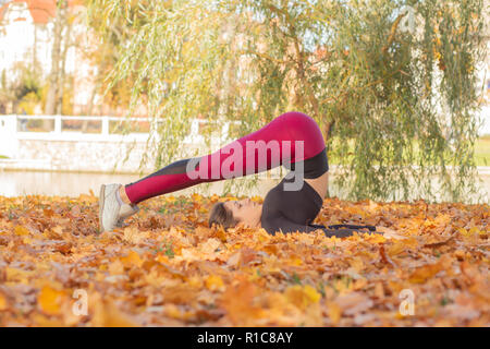 Sport junge Frau übt Yoga im Herbst City Park Stockfoto