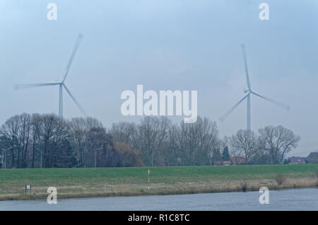 Zwei Windkraftanlagen bei bewölktem Himmel über Bäume, Hamburg drehen, Deutschland Stockfoto