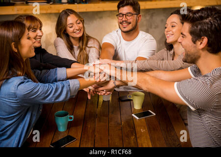 Eine Gruppe von Freunden in seine Hände zusammen im Cafe Stockfoto