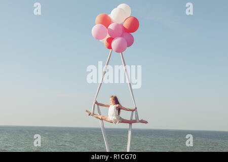 Kleines Mädchen Acrobat tun die Splits auf den Leinwänden. Ballons halten Leinwände. Stockfoto