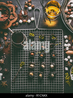 Hausgemachte Schokolade Pralinen Vorbereitung auf dunklen rustikalen Tisch Hintergrund mit Vintage Küchengeräte und Zutaten. Pflaumen mit Nüssen gefüllt Stockfoto