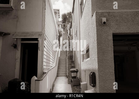 Eine Treppe führt nach oben zwischen zwei hohen Wänden in Schwarzweiß Stockfoto