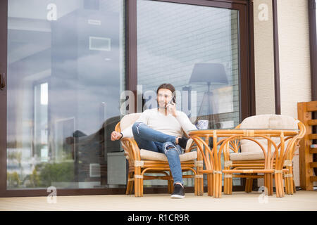 Männliche sitzen auf im freien Sessel und sprechen über das Telefon Stockfoto