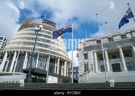 Fahnen flattern vor der Neuseeländischen Regierung Gebäude, Haus neo-klassischen Stil Haus des Parlaments mit Bienenstock hinter sich. Stockfoto