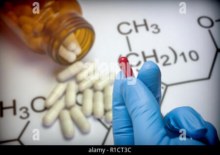 Hand mit Handschuh blau Latex unterstützt die rote Kapsel, konzeptionelle Bild Stockfoto