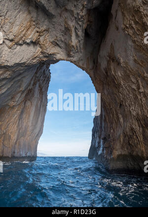 Arch in der berühmten Meer stack (Faraglione di Mezzo) vor der Küste von der Insel Capri im Mittelmeer, in Süditalien. Stockfoto