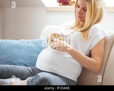 Schwangere Frau auf dem Sofa zu Hause sitzen Stockfoto