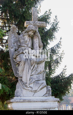 Ein Grabstein eines Engels mit einem Kreuz auf dem Friedhof Stockfoto