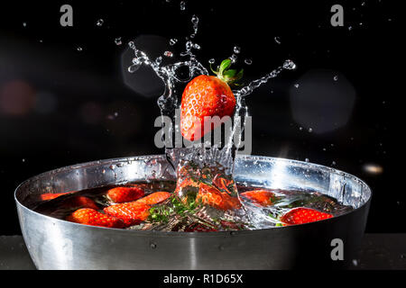 Erdbeere ins Wasser zu fallen mit spritzt Wasser auf einem schwarzen Hintergrund Stockfoto