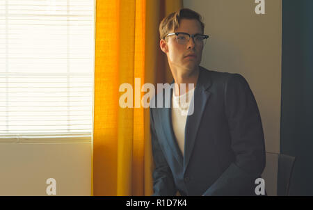 Ein junger Mann, Mann im blauen Anzug und weissen Hosen, trägt ein Paar vintage Gläser, entfernt. Ein Männer Jahrgang redaktionelles Konzept Stockfoto