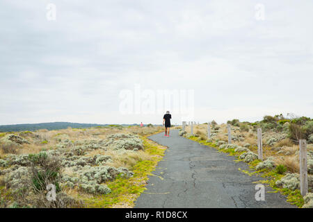 Einsamer Mann laufen auf einem leeren Pfad, weit weg von der Kamera. Stockfoto