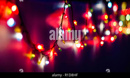 Dekorative Bunte verwischt Christmas Lights auf dunklem Violett unterlegt. Abstrakte sanfter Beleuchtung. Bunte helle Kreise eines funkelnden Girlande Stockfoto