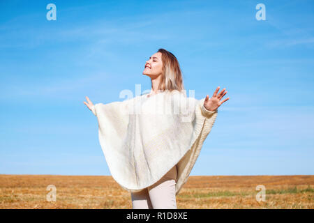 Fröhliches Mädchen mit erhobenen Händen auf dem Feld in warmen Herbst. Stockfoto