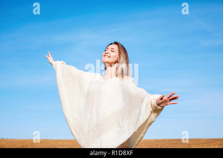 Fröhliches Mädchen mit erhobenen Händen auf dem Feld in warmen Herbst. Stockfoto