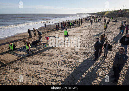 Gorleston-On - Meer, Norfolk. 11. November 2018. Menschenmengen auf Gorleston Strand versammeln sich Danny Boyle's Allgemein "Seiten der Erinnerung" zu beteiligen, markiert das Ende des Ersten Weltkriegs vor 100 Jahren, viele Ihrer eigenen künstlerischen Beiträge im Sand der Erinnerung an die Personen, die unsere Ufer links und kehrte nie zurück. Credit: Adrian Buck/Alamy leben Nachrichten Stockfoto