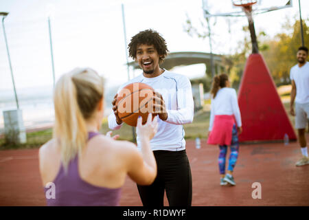 Gemischtrassiges Paar Basketball spielen im Freien Gericht am outumn Tag Stockfoto