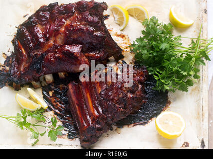 Appetitlich gebackene verglaste Kalb- oder Schweinefleisch Rippen mit Zitrone und Kräutern serviert. Selektive konzentrieren. Stockfoto